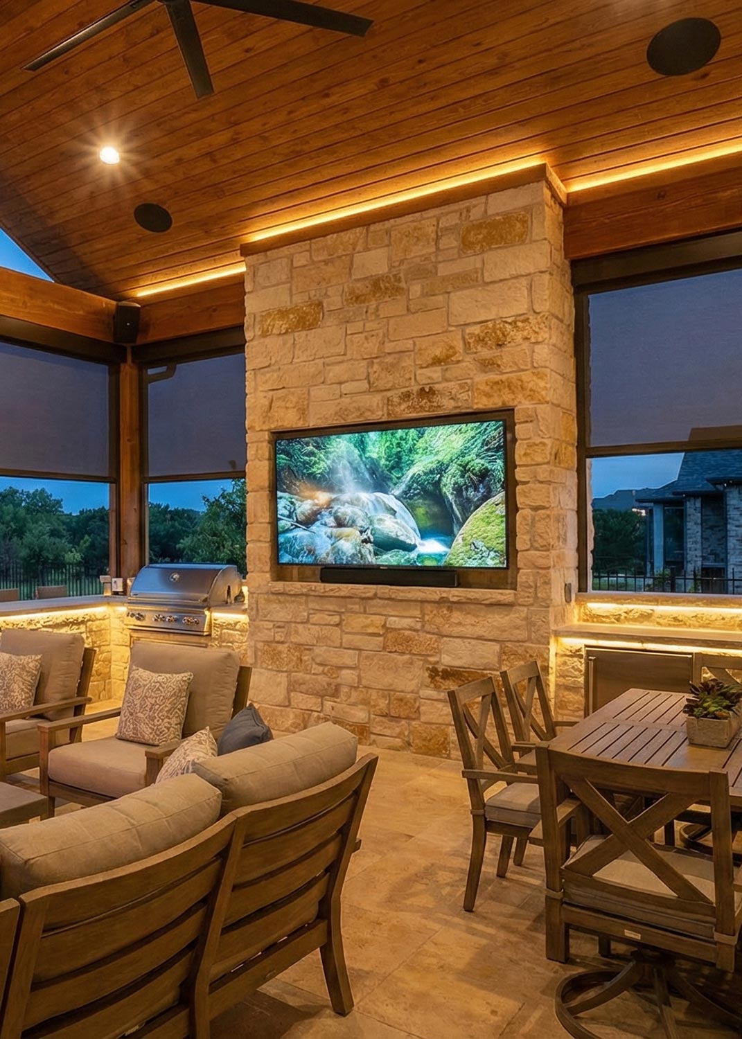 Covered patio with comfortable seating and a wall-mounted TV over a stone fireplace