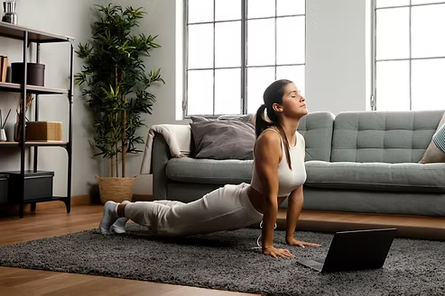 Woman stretching on a living room floor in front of a sofa and bookshelf