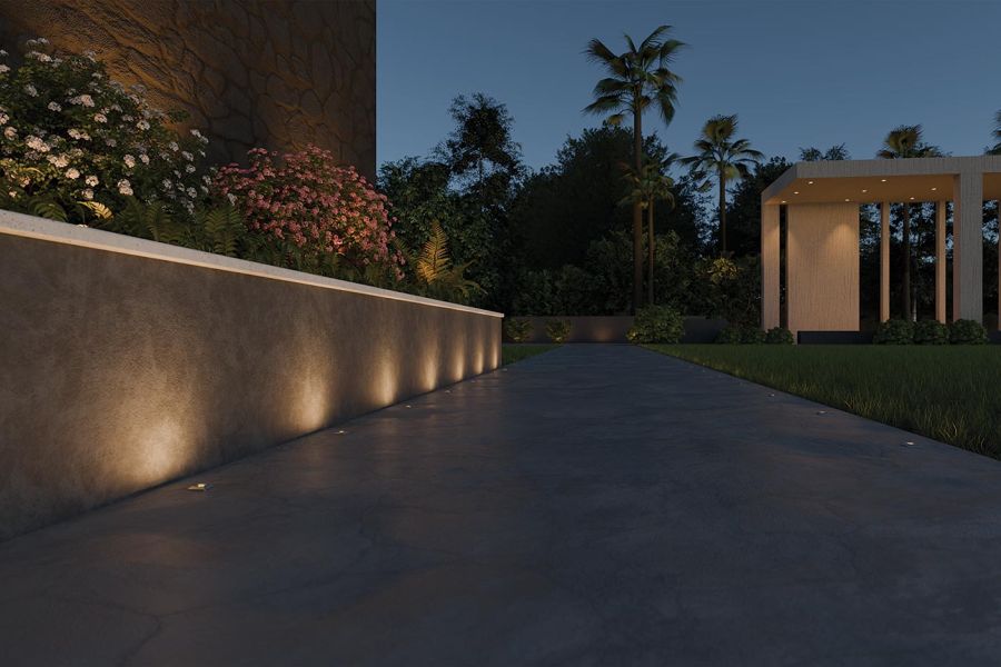 Low wall and pathway illuminated by recessed ground lights at dusk
