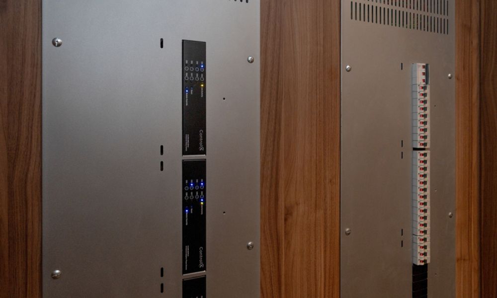 <span class="uk-h4">Equipment cabinet with wood and metal panels housing rack-mounted smart home gear</span>