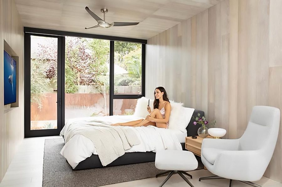 Woman relaxing on bed in a bedroom with large window