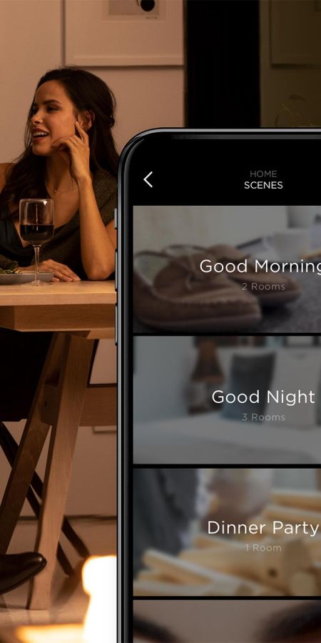 Smartphone screen showing smart home scene options with a woman dining in the background